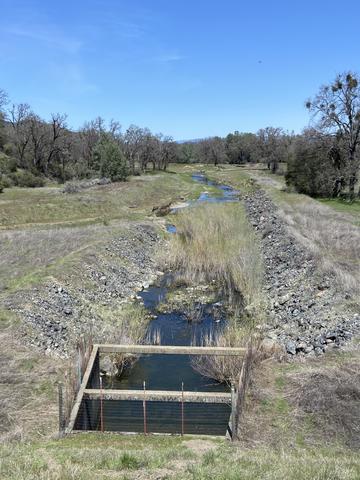 Adobe Creek winding through Big Valley floor with rock-armored banks and Mayacamas Mountains in background